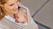 Baby vilar i bärsjal hos sin mamma.
