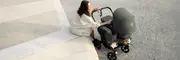 Kvinna med barnvagn som utför underhåll och skötsel av sin barnvagn.