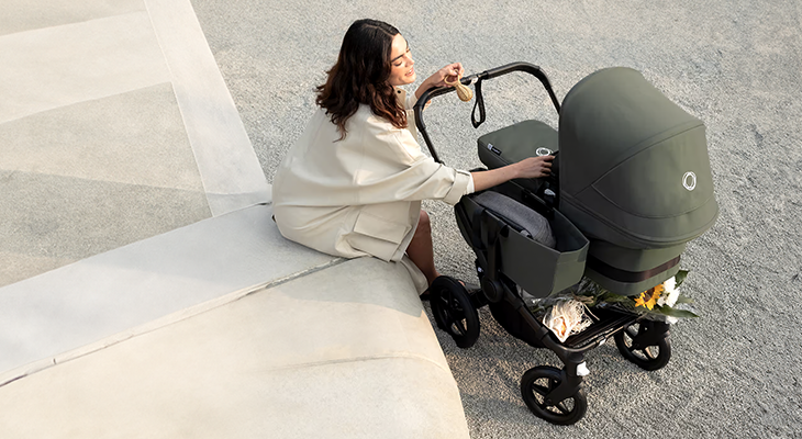 Mamma sitter och tittar på sin bebis i sin Bugaboo Donkey 6-barnvagn